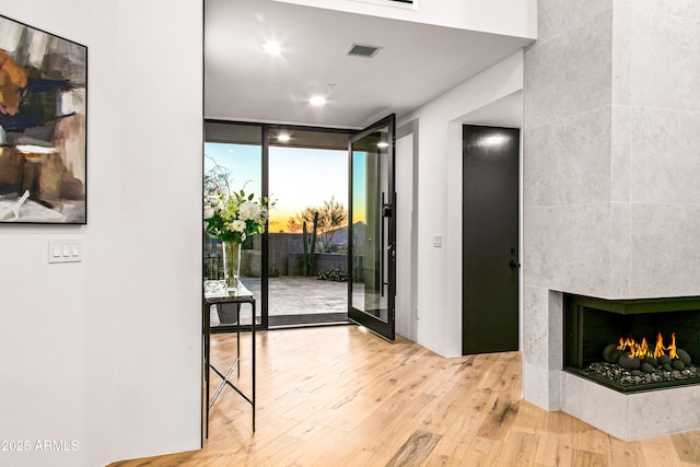 doorway with a fireplace, visible vents, wood finished floors, and floor to ceiling windows