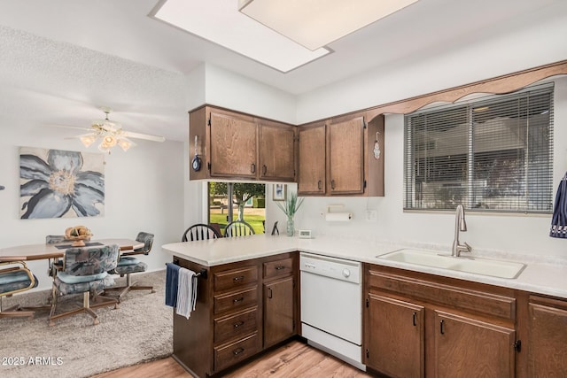 kitchen featuring sink, light hardwood / wood-style flooring, dishwasher, ceiling fan, and kitchen peninsula