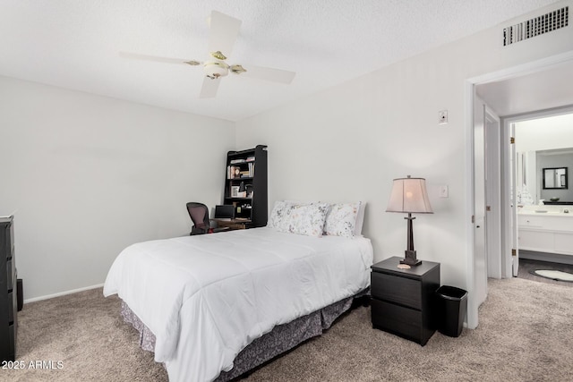 carpeted bedroom with a textured ceiling, ceiling fan, and ensuite bath