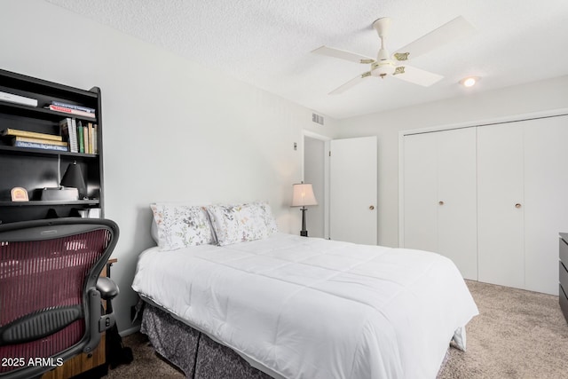 bedroom featuring ceiling fan, carpet flooring, a closet, and a textured ceiling