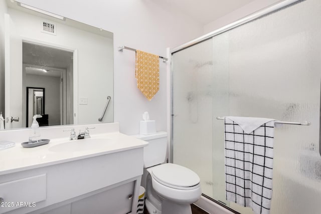 bathroom with vanity, a shower with shower door, and toilet