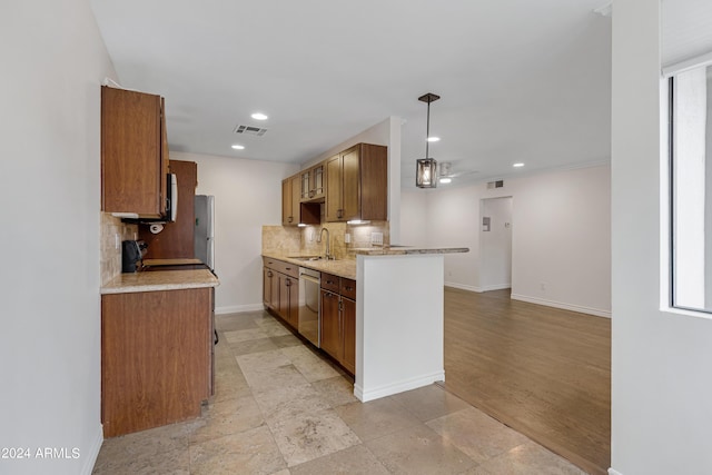 kitchen with sink, decorative light fixtures, stainless steel appliances, light stone countertops, and backsplash