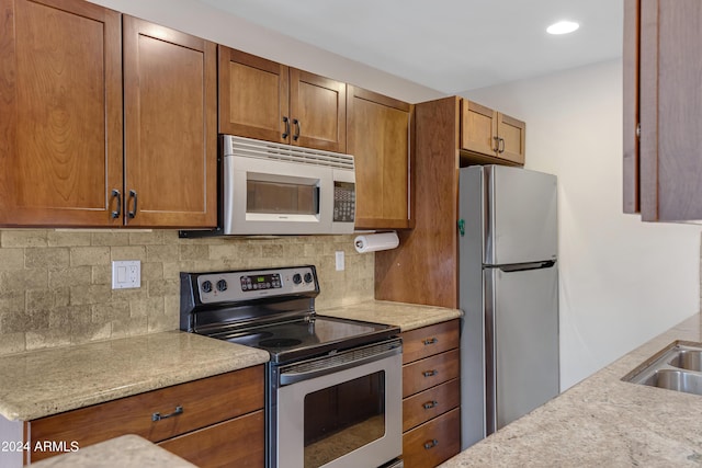 kitchen featuring light stone countertops, decorative backsplash, and stainless steel appliances