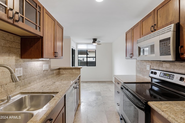 kitchen featuring sink, white appliances, light stone countertops, and backsplash