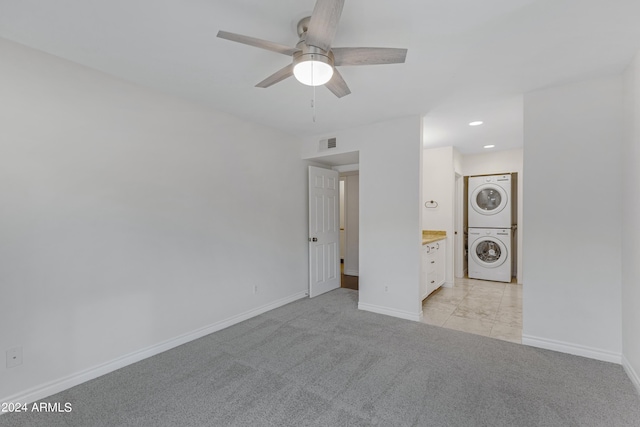 spare room featuring ceiling fan, stacked washing maching and dryer, and light carpet