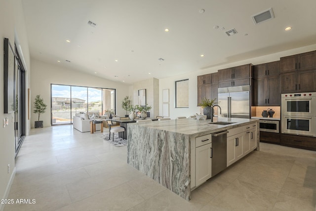 kitchen featuring a sink, appliances with stainless steel finishes, light stone countertops, visible vents, and recessed lighting