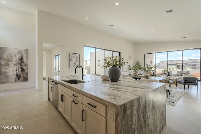 kitchen featuring recessed lighting, stainless steel dishwasher, light stone counters, and a sink
