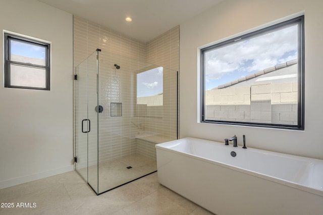bathroom with recessed lighting, tile patterned flooring, a freestanding bath, baseboards, and a stall shower