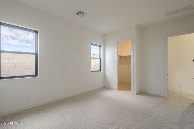 unfurnished bedroom featuring light colored carpet, multiple windows, and visible vents