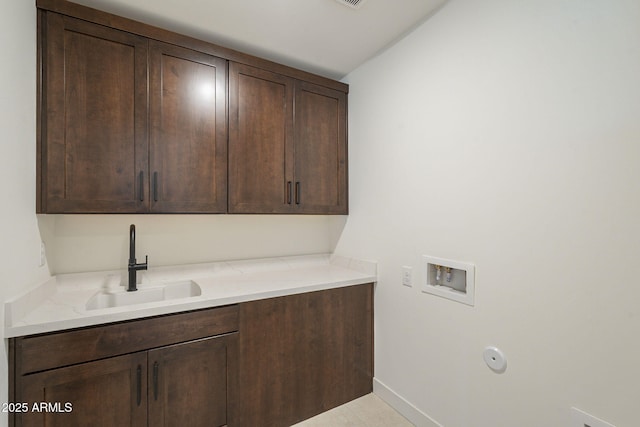 laundry room featuring cabinet space, washer hookup, baseboards, and a sink
