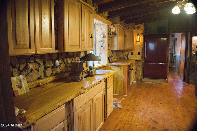 kitchen with butcher block counters, light hardwood / wood-style floors, beamed ceiling, and decorative light fixtures