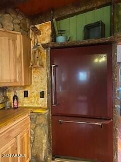 kitchen featuring tasteful backsplash, light brown cabinetry, and refrigerator