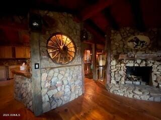 bar with beam ceiling, a stone fireplace, and hardwood / wood-style floors