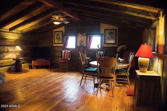 dining area with wood walls, lofted ceiling with beams, hardwood / wood-style flooring, and ceiling fan