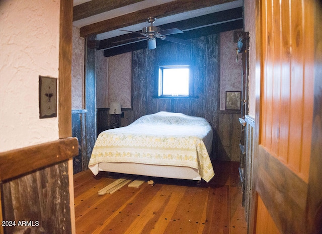 bedroom with ceiling fan, beamed ceiling, and hardwood / wood-style floors