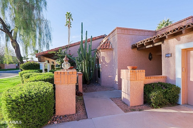 exterior space featuring stucco siding and a tiled roof