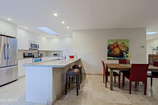 kitchen featuring white cabinetry, a breakfast bar area, stainless steel appliances, and a sink