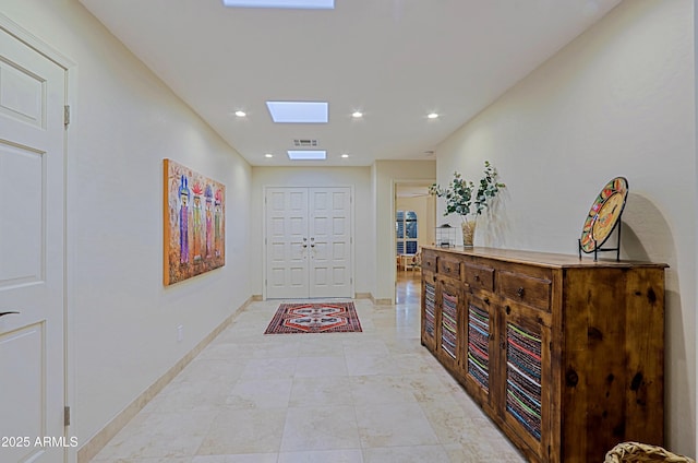 hall featuring recessed lighting, visible vents, baseboards, and a skylight