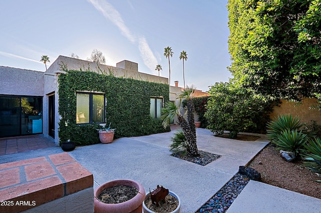 view of front facade featuring a patio, fence, and stucco siding