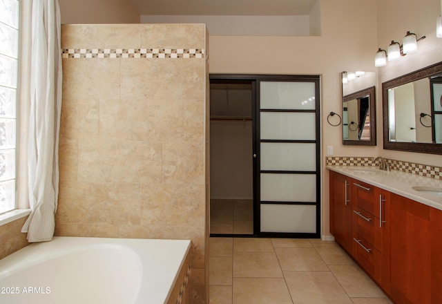 bathroom featuring tile patterned floors, a garden tub, double vanity, and tile walls