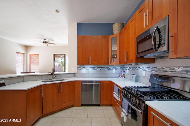 kitchen with appliances with stainless steel finishes, a sink, brown cabinets, and backsplash