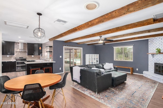 dining room featuring beamed ceiling, a brick fireplace, wood finished floors, and visible vents