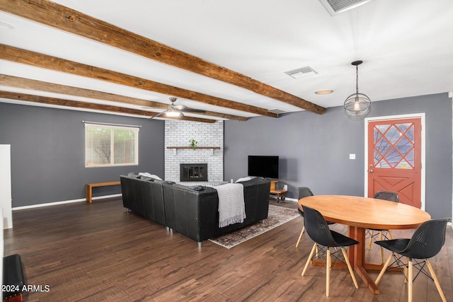 living area with dark wood-style flooring, visible vents, a brick fireplace, beamed ceiling, and baseboards