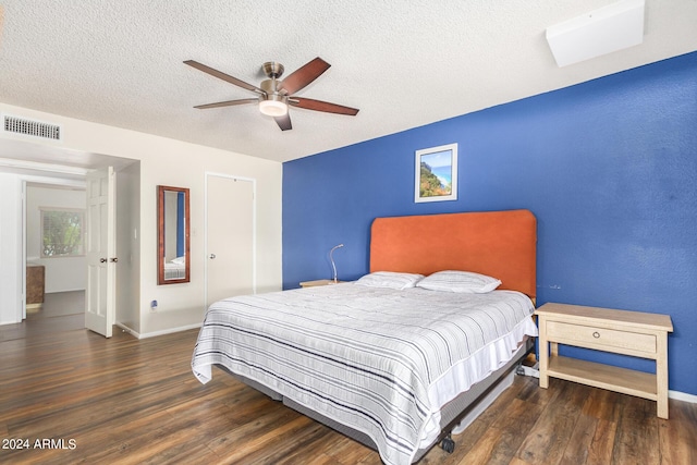 bedroom with visible vents, dark wood-type flooring, ceiling fan, a textured ceiling, and baseboards