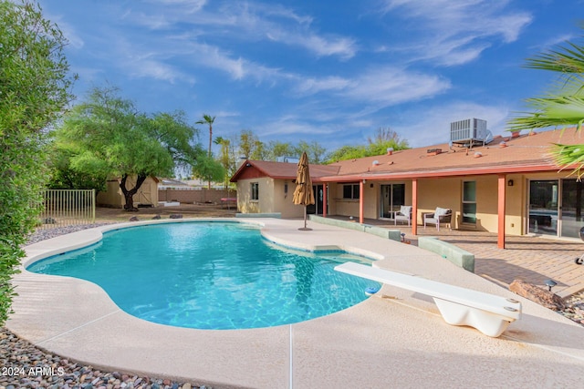 view of swimming pool with central AC unit, a fenced in pool, fence, a patio area, and a diving board