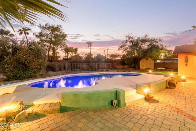 pool at dusk featuring a fenced backyard, a fenced in pool, and a patio