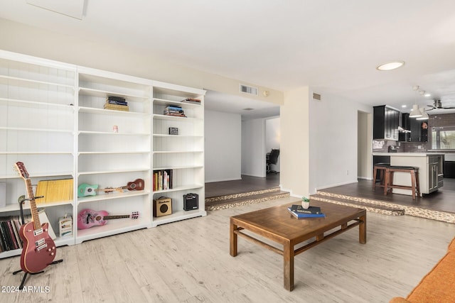 living area with light wood-style flooring, visible vents, and baseboards