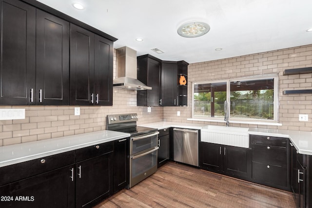 kitchen with wall chimney exhaust hood, stainless steel appliances, light countertops, open shelves, and a sink