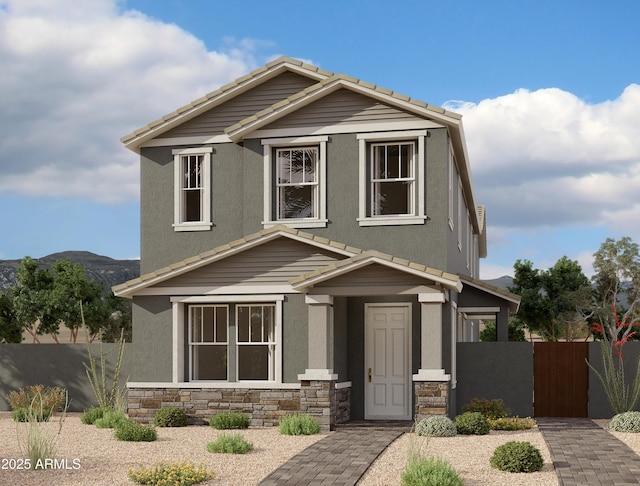 view of front of property featuring fence, a tiled roof, stucco siding, stone siding, and a mountain view