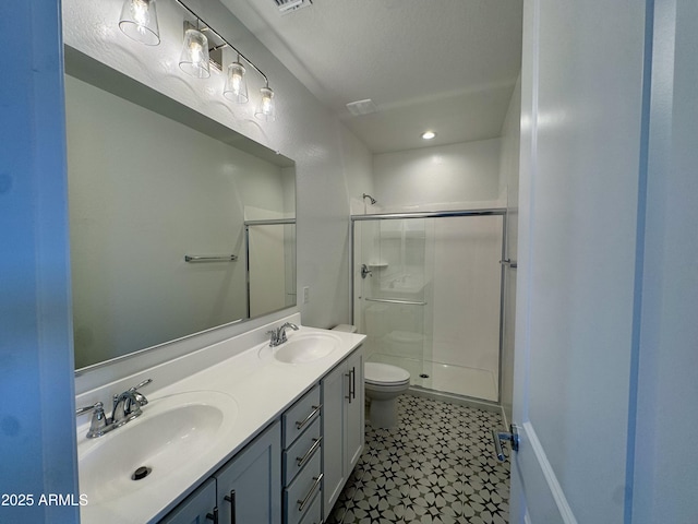 full bathroom featuring double vanity, toilet, a stall shower, and a sink