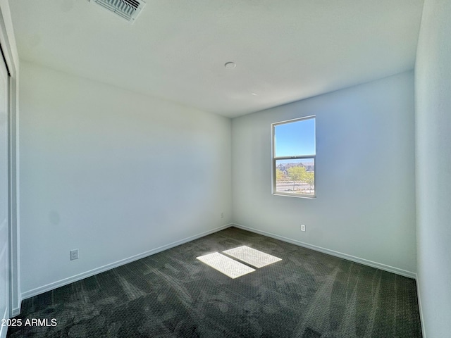 empty room featuring visible vents, baseboards, and dark colored carpet