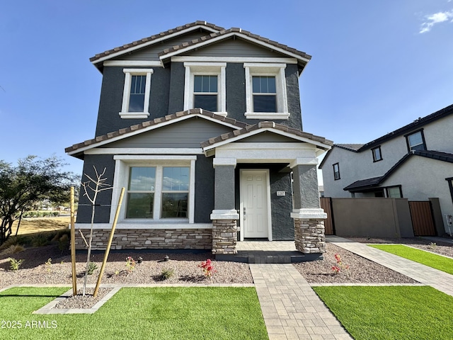 view of front facade featuring a tiled roof, fence, and stone siding