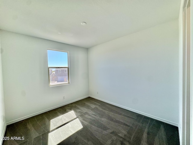 empty room with baseboards and dark colored carpet