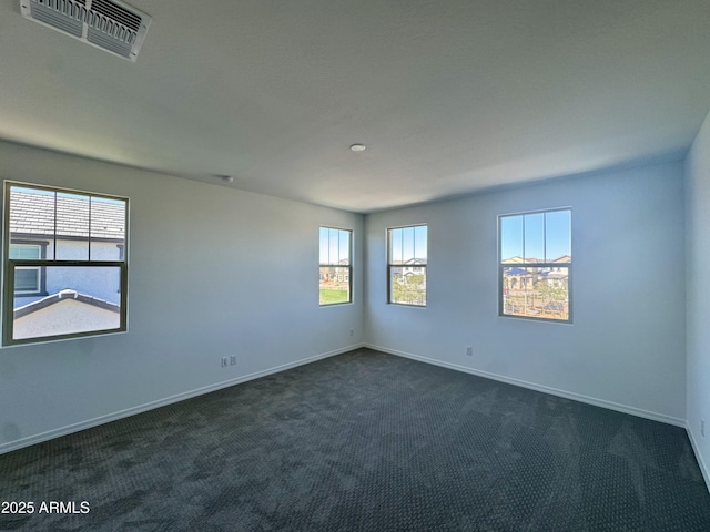 unfurnished room with dark colored carpet, visible vents, and baseboards