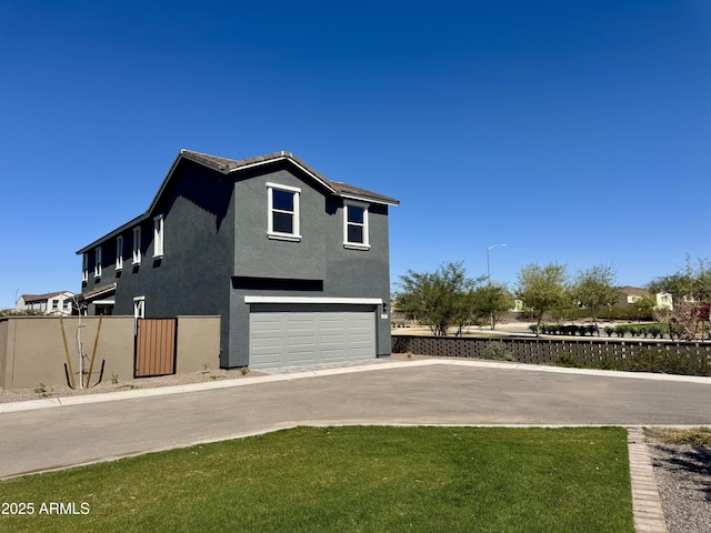 view of side of property featuring fence, stucco siding, a lawn, driveway, and an attached garage