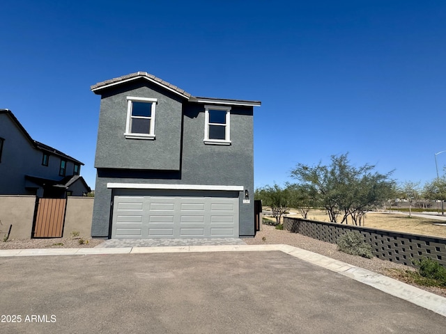 view of front of house with stucco siding, an attached garage, and fence