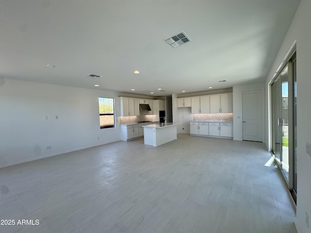 kitchen with decorative backsplash, open floor plan, visible vents, and white cabinets