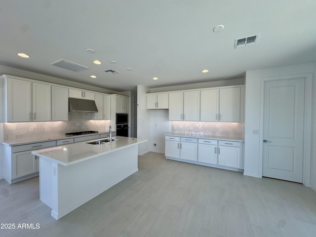 kitchen with visible vents, under cabinet range hood, and a sink