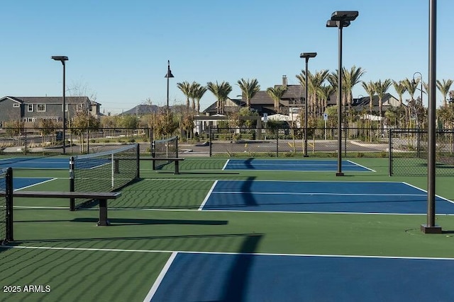 view of tennis court featuring fence and a residential view