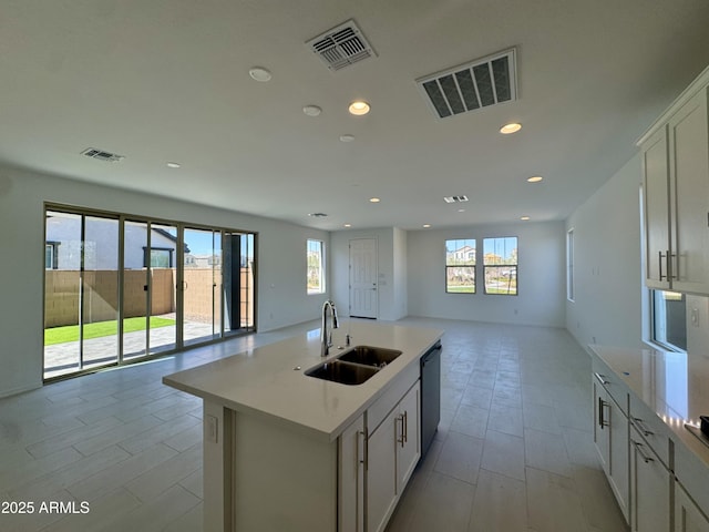 kitchen with open floor plan, dishwashing machine, visible vents, and a sink