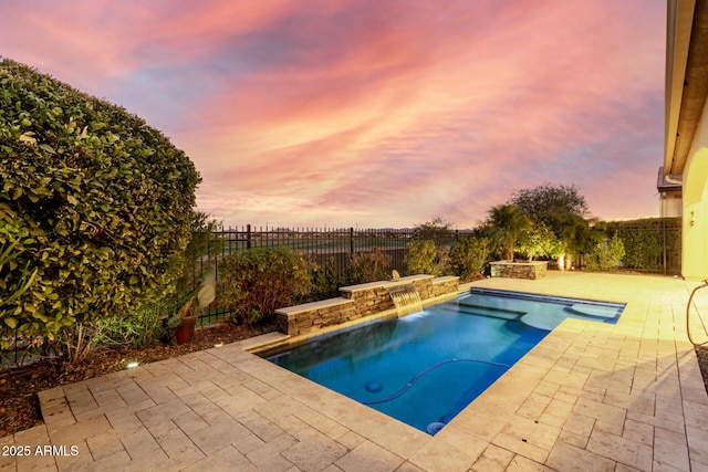 pool at dusk featuring a patio and pool water feature