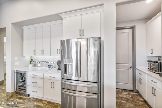 kitchen with wine cooler, white cabinetry, stainless steel fridge, and decorative backsplash