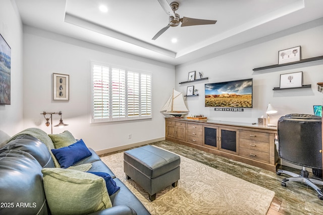 office area with a tray ceiling and ceiling fan