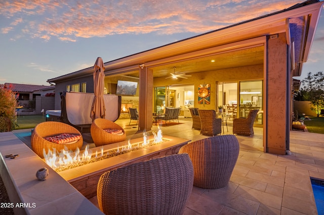 patio terrace at dusk featuring an outdoor living space with a fire pit and ceiling fan