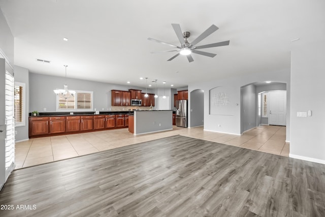 16763 W Magnolia St, Goodyear, AZ 85338 - unfurnished living room with arched walkways, light wood-type flooring, a chandelier, a ceiling fan, and baseboards