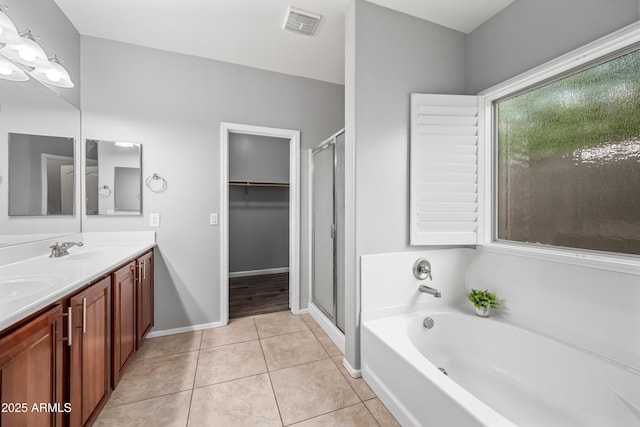 16763 W Magnolia St, Goodyear, AZ 85338 - full bathroom with double vanity, a bath, tile patterned flooring, a stall shower, and baseboards